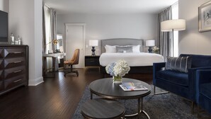 A hotel room with a bed, a desk, a chair, a sofa, a coffee table, and a TV. - Seven Gables, St. Louis West, a Tribute Portfolio Hotel (St. Louis)