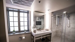A modern bathroom with a large window, a walk-in shower, and a vanity with a mirror. - Seven Gables, St. Louis West, a Tribute Portfolio Hotel (St. Louis)