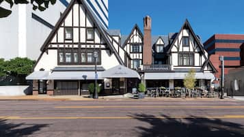 Traditional Tudor-style building with a gabled roof and brick chimney, featuring a central entrance with a canopy and series of windows.