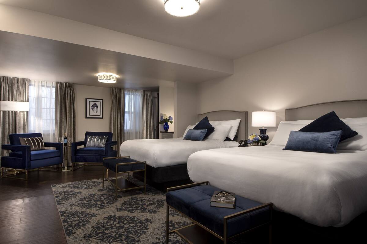 A hotel room with two beds, a sofa, a coffee table, and a rug.