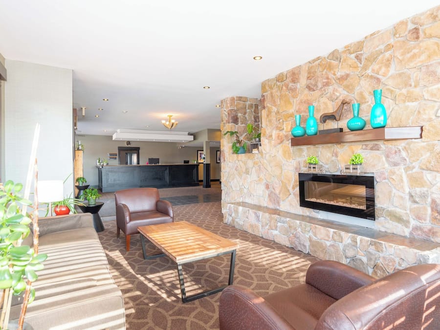 A modern lounge area with leather sofas, a wooden coffee table, and a stone fireplace with decorative vases.