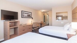 Hotelkamer met twee bedden, een bureau met stoel, een televisie, een klein tafeltje en een spiegel.