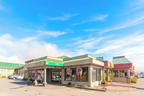 A lobby area with a green sign, a clear entrance, and hanging flower baskets.