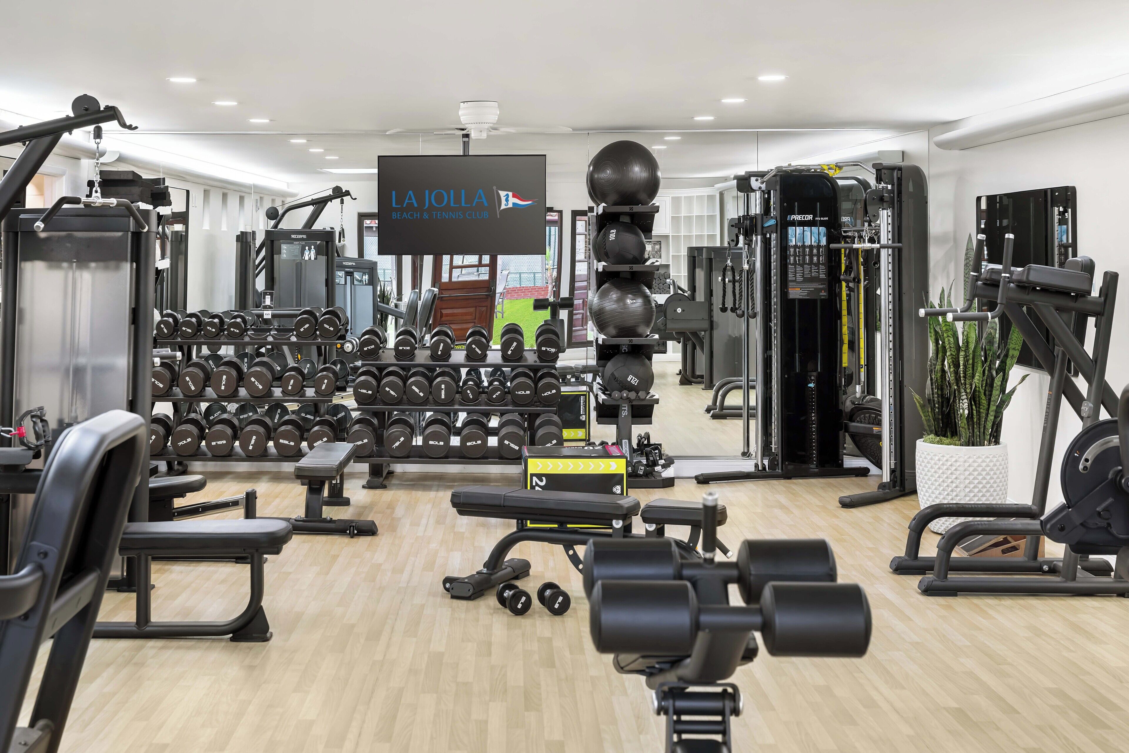 A gym with various exercise equipment, including dumbbells, benches, and weight machines.