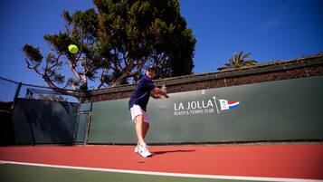 A tennis court with a net, a player in mid-action, and a banner with "LA JOLLA BEACH & TENNIS CLUB" text.