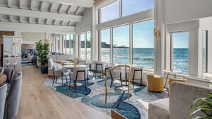 A spacious indoor area with large windows overlooking the ocean, featuring modern furniture and a wooden floor. - La Jolla Beach and Tennis Club (La Jolla)
