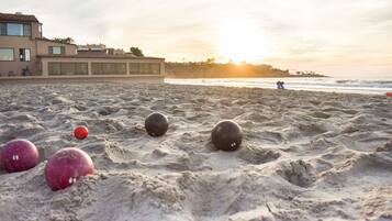 Una playa con arena, un edificio y un atardecer.