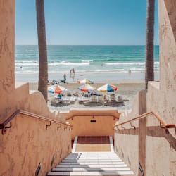 Stairs lead to a beach area with a clear view of the ocean.