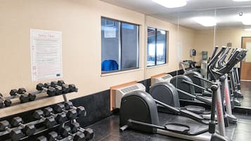 Ein Fitnessraum mit Laufbändern, Kurzhanteln und einem Sicherheitsposter an der Wand.