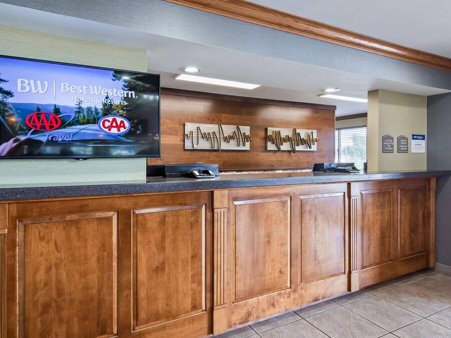 A reception area with a flat-screen TV displaying a travel advertisement, wooden cabinets, and a tiled floor.