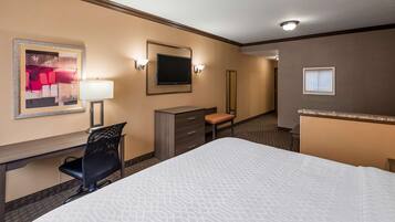 Une chambre d’hôtel équipée d’un lit, d’un bureau, d’une chaise, d’une commode et d’un téléviseur.
