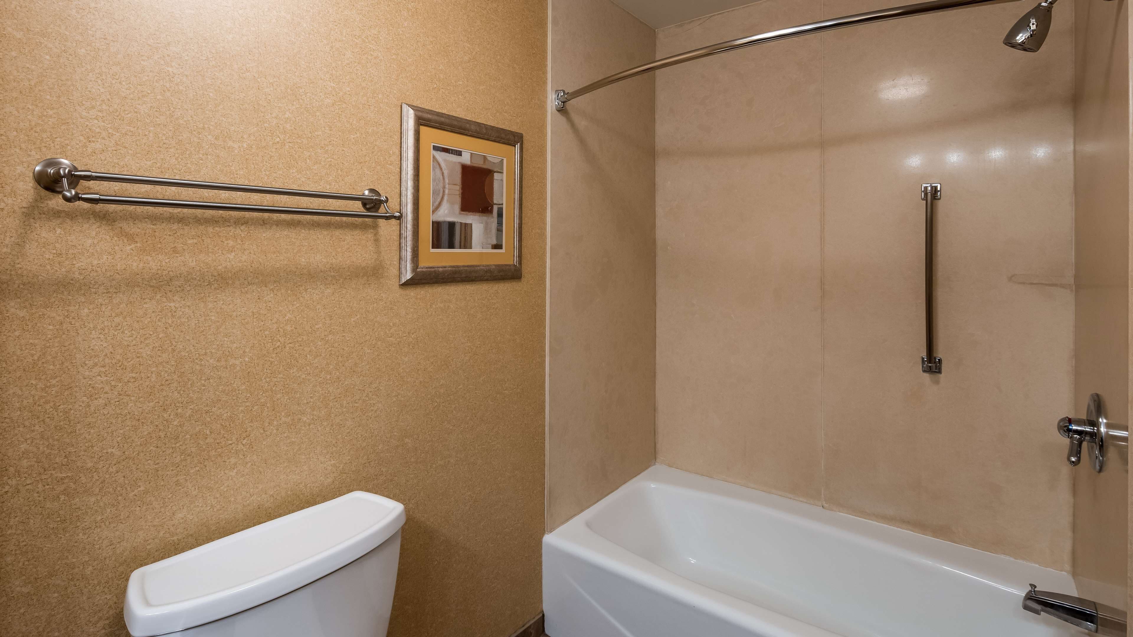Une salle de bain comprenant des toilettes, une douche avec une porte en verre et un porte-serviettes.