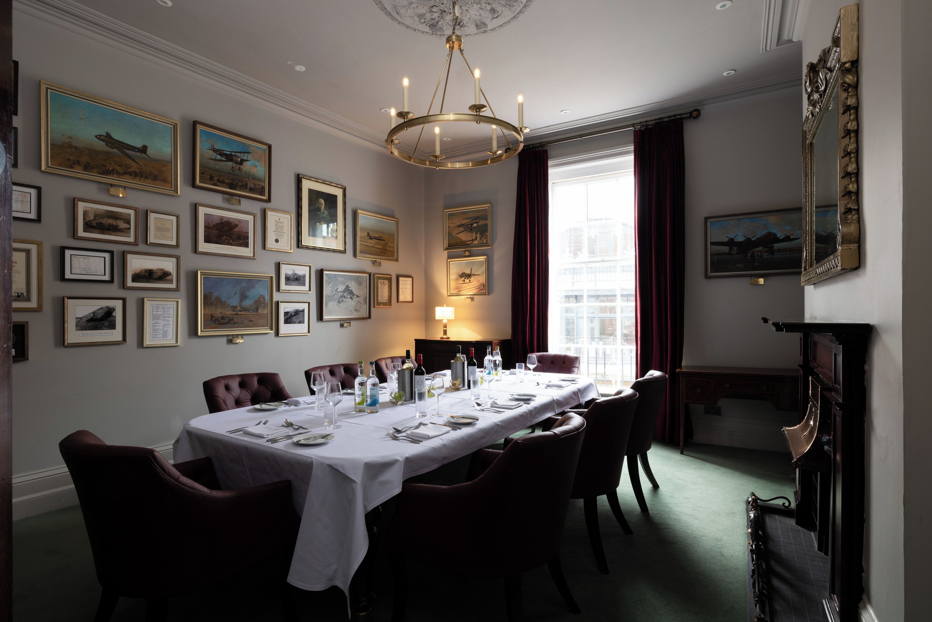 A dining room with a long table set for a meal, framed pictures on the walls, and a chandelier.
