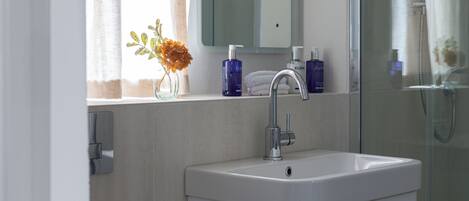 A bathroom with a white sink, a mirror, and a glass shower enclosure.