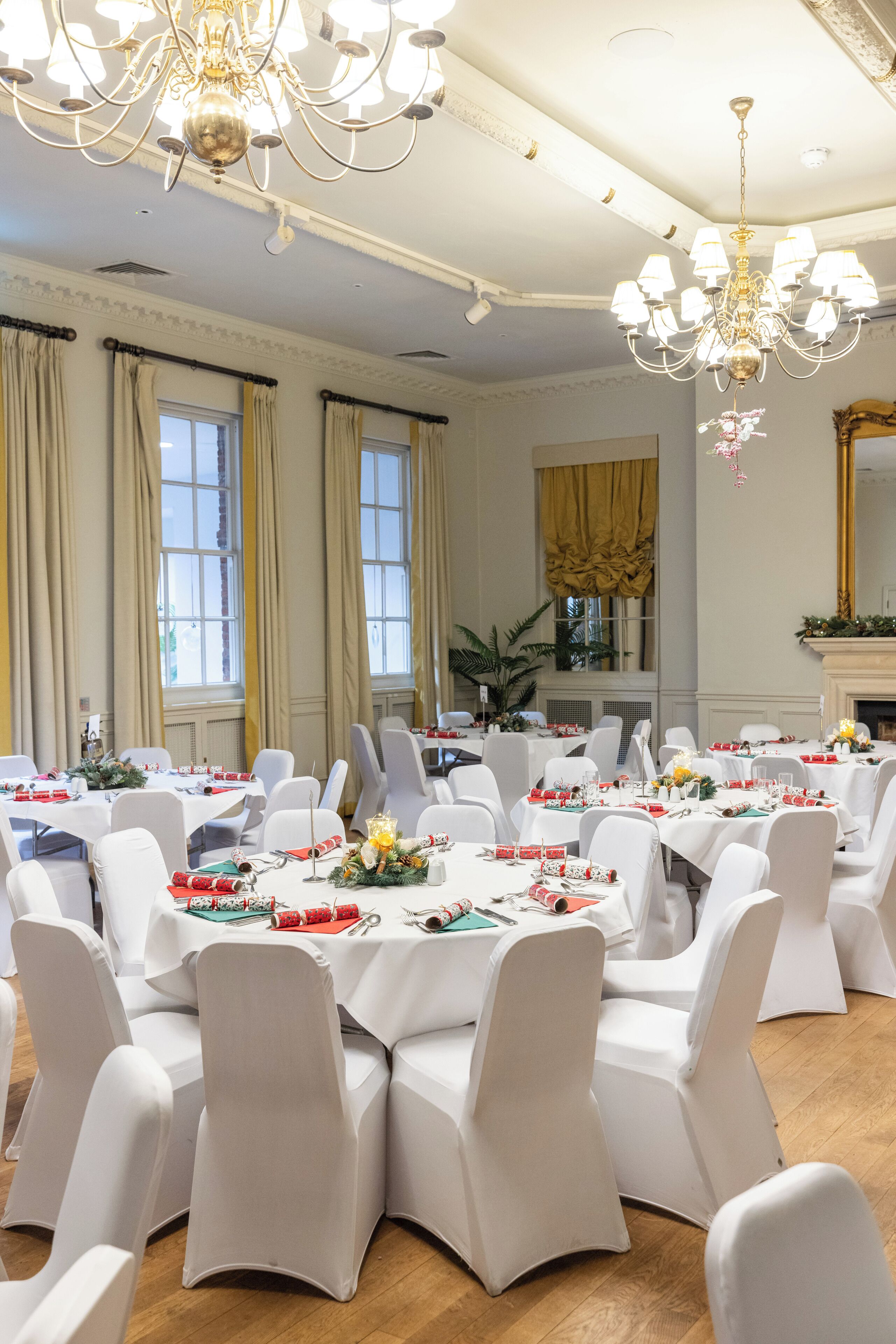 Un comedor formal con mesas redondas, sillas blancas y candelabros.