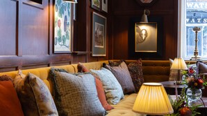 A cozy seating area with a sofa, a round wooden table, and a lamp. - White Hart Hotel (Lincoln)