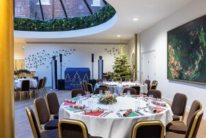Comedor con mesas redondas, sillas y un árbol de Navidad.