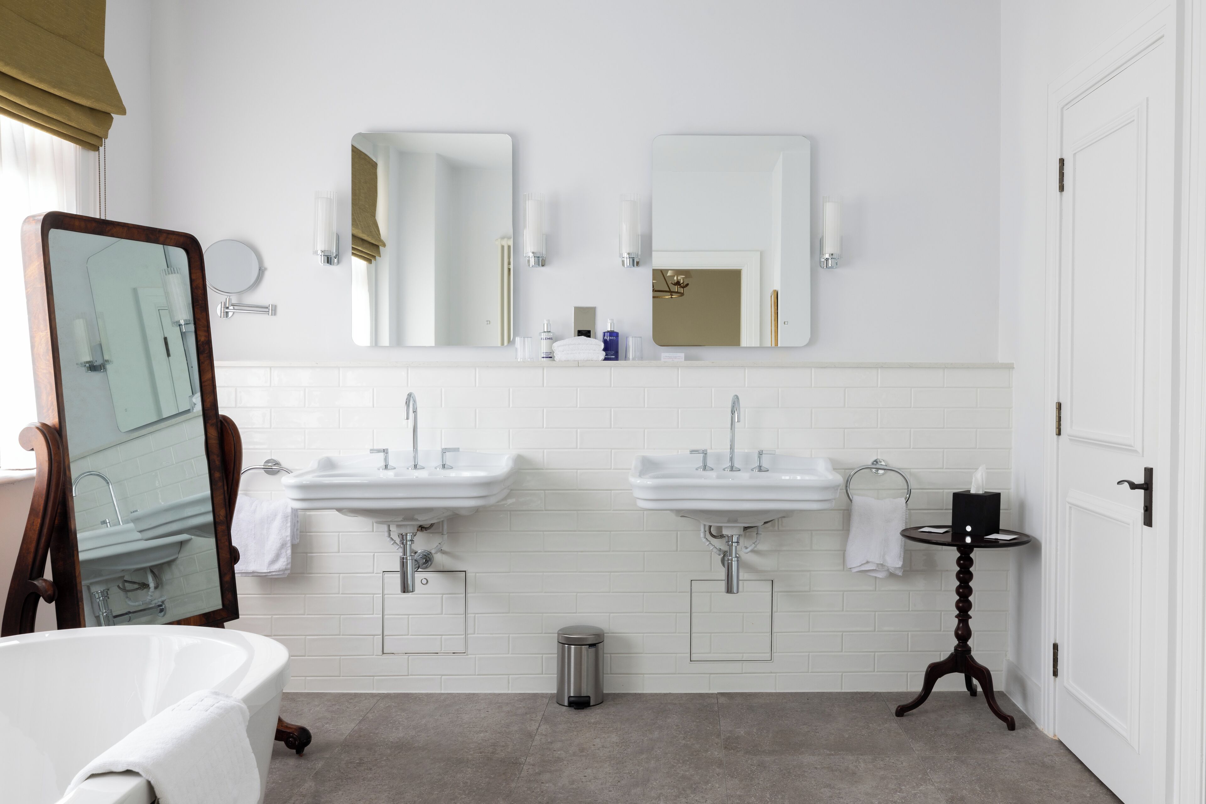 A bathroom with two sinks, a bathtub, and a mirror.