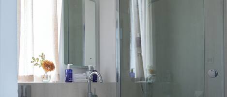A modern bathroom with a toilet, sink, and glass-enclosed shower.