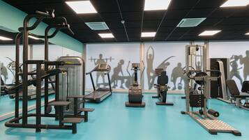 Une salle de sport équipée de divers appareils d’entraînement, notamment des tapis de course, des appareils de musculation et un support à squats.