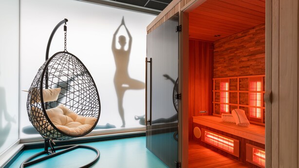 A room with a hanging chair, a sauna area with benches and heaters, and a glass partition. - Thon Hotel Bristol Stephanie (Brussels)