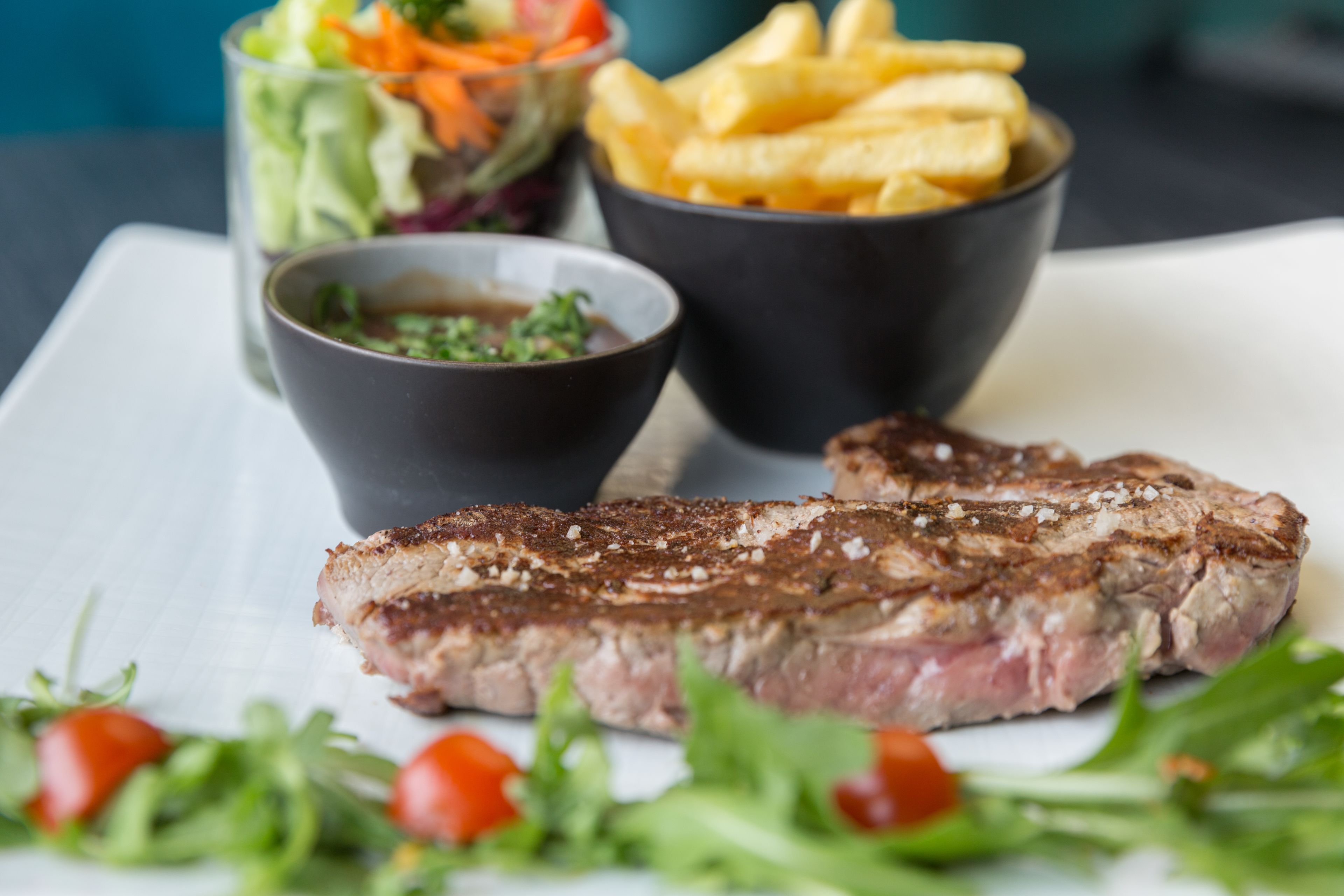 Un plato con bistec, papas fritas y una ensalada.