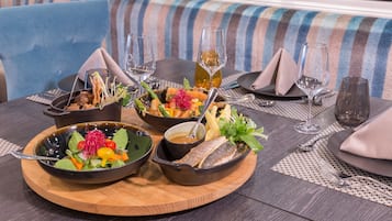 Una mesa de comedor con tres fuentes de comida, cada una con un plato diferente, y dos copas de vino.