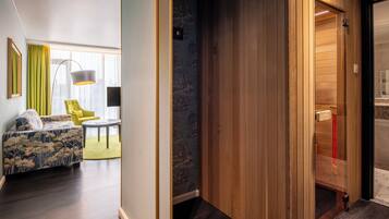 A modern hotel room with a wooden wardrobe, a sofa with floral upholstery, and a yellow armchair.