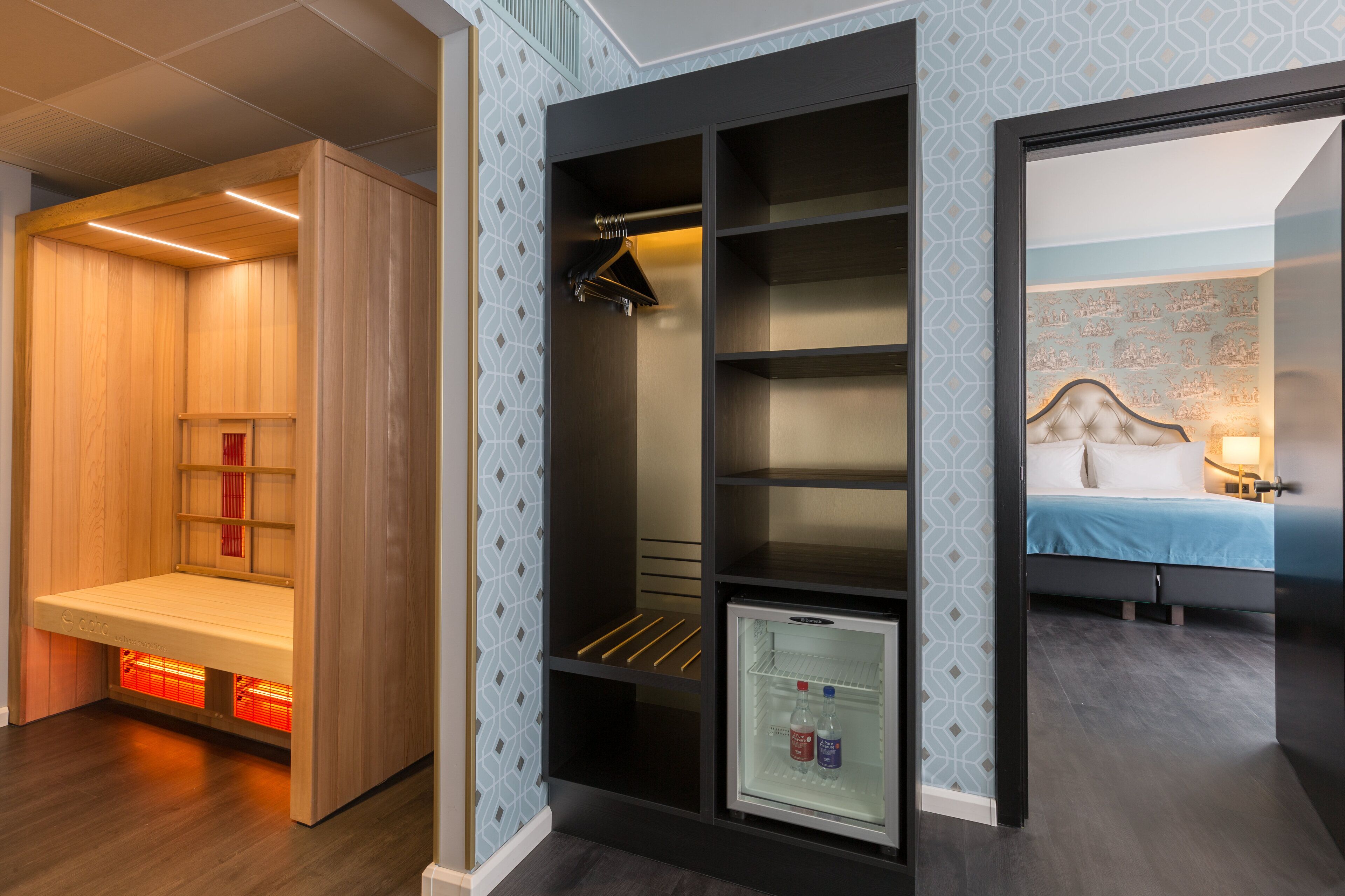 Une chambre d’hôtel dotée d’un sauna intégré, d’un dressing et d’un lit avec une table de chevet.