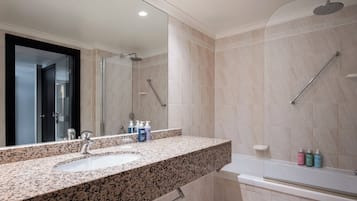 A modern bathroom with a granite countertop, a sink, a mirror, a shower, and a bathtub.