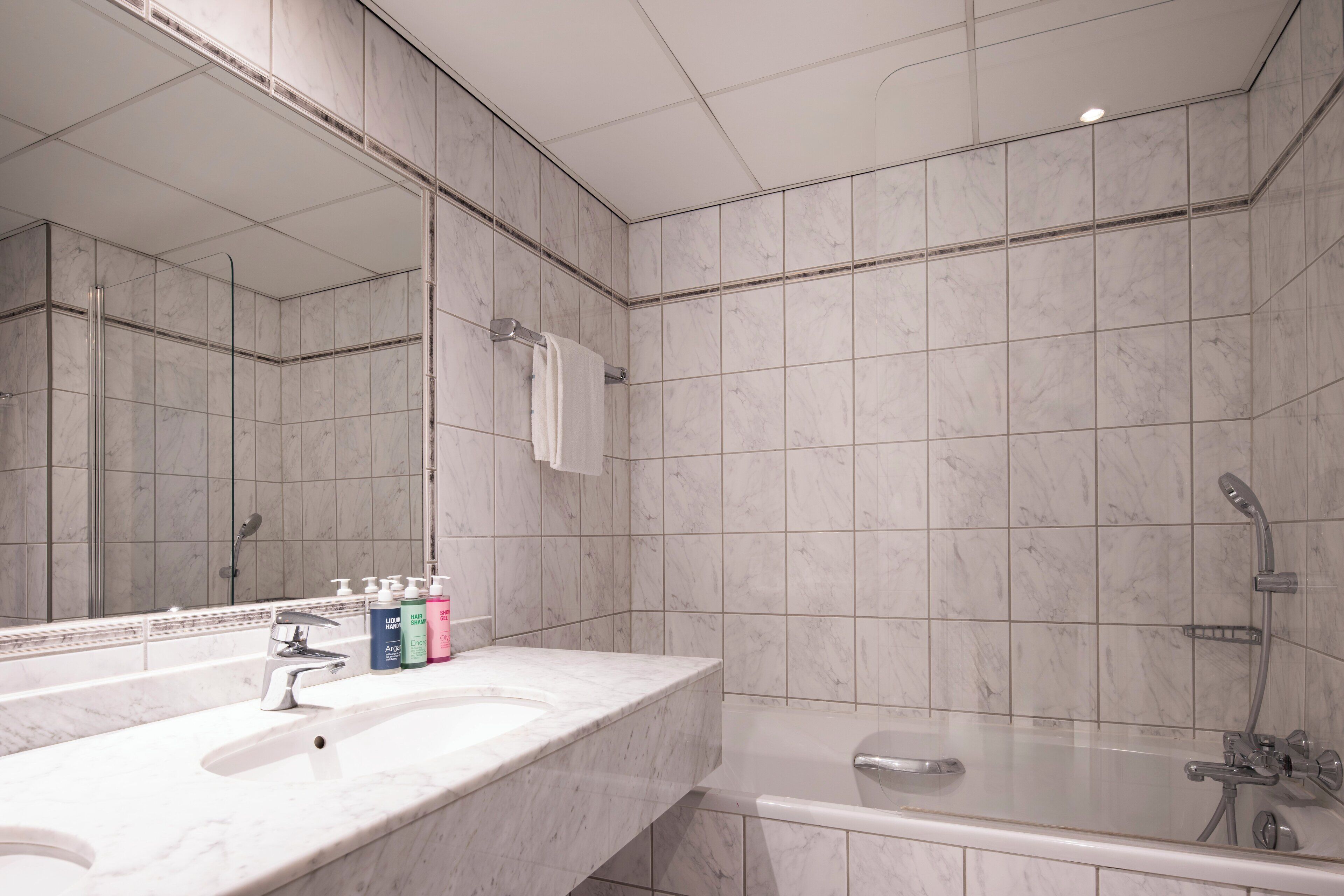 Une salle de bain moderne avec un lavabo en marbre, un grand miroir, une baignoire et une douche.