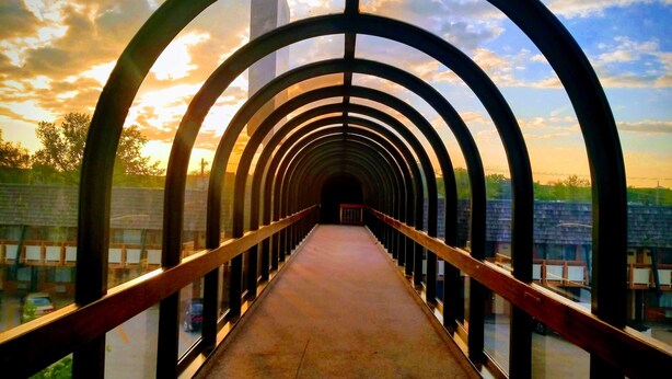 A pedestrian bridge with a metal arch design, featuring a walkway and railings. - Best Western Sheridan Center (Sheridan)