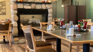 A restaurant with a stone fireplace, wooden chairs, and tables set with condiments and glasses. - Best Western Sheridan Center (Sheridan)