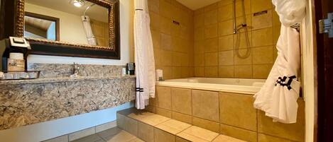 A bathroom with a marble sink, a large mirror, a bathtub, and a shower.