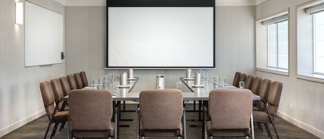 A conference room with a large screen, multiple chairs, and a projector.