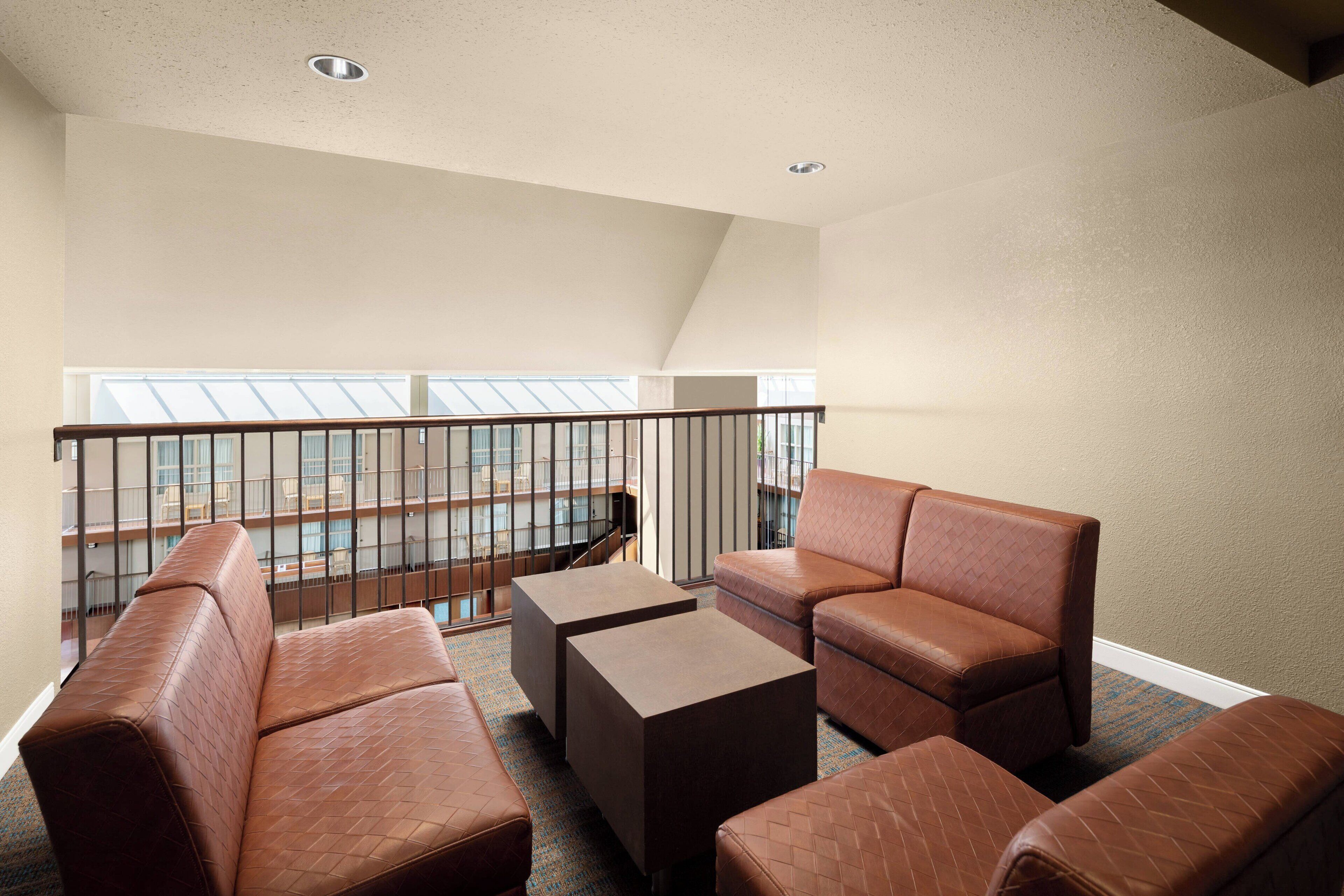 Ein Zimmer mit hohen Decken, einem Balkon, Ledersofas, einem Couchtisch und Blick auf die Stadt.