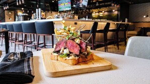 A restaurant setting with a bar area in the background, featuring multiple screens and seating arrangements. - Delta Hotels by Marriott Calgary South (Calgary)