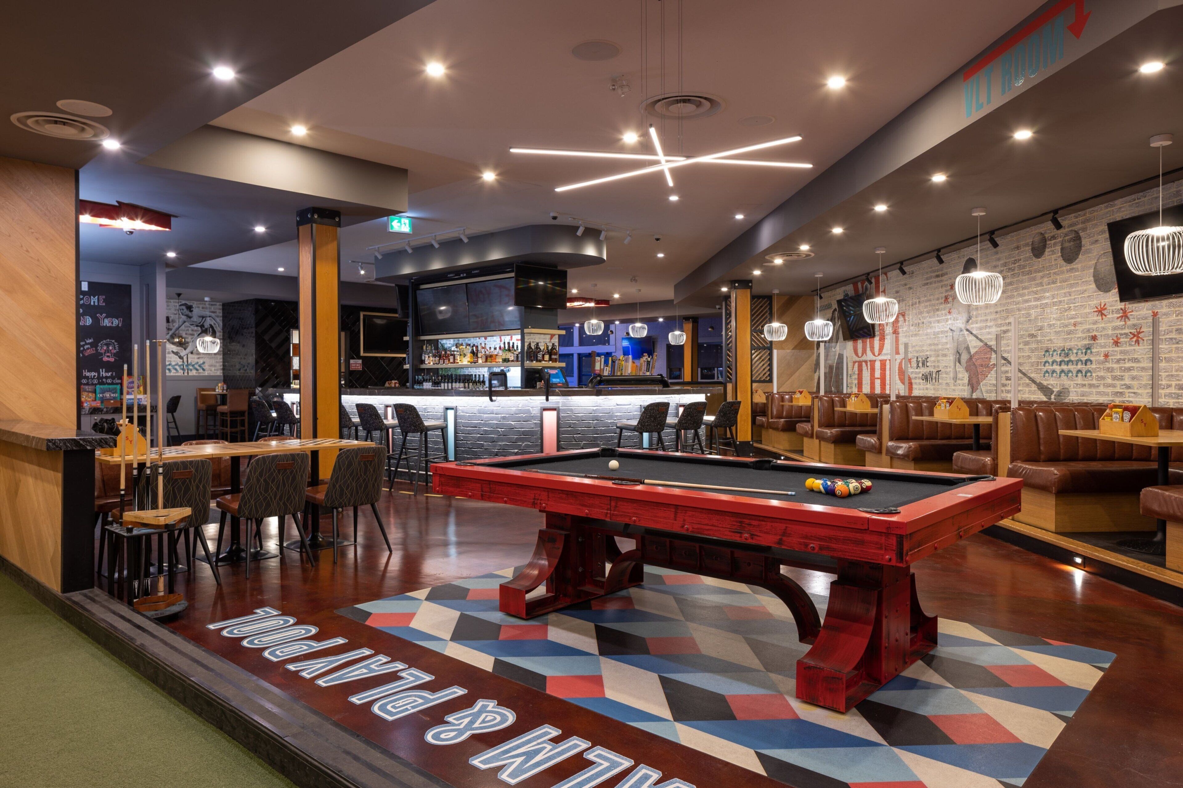Une table de billard dans un espace de détente moderne, avec un bar et des sièges.