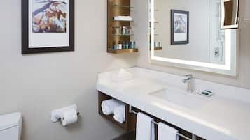 Un baño moderno con un lavamanos blanco, un espejo grande y un cuadro enmarcado en la pared.