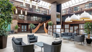 A spacious indoor atrium with a central staircase, multiple levels, and a variety of seating areas. - Delta Hotels by Marriott Calgary South (Calgary)