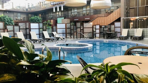 A hotel pool area with lounge chairs, a circular hot tub, and modern lighting fixtures. - Delta Hotels by Marriott Calgary South (Calgary)