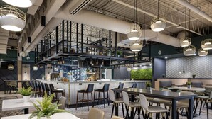 A modern restaurant with high ceilings, exposed ductwork, and a mix of bar seating and dining tables. - Delta Hotels by Marriott Calgary South (Calgary)