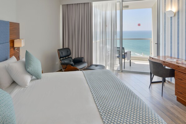 A hotel room with a bed, a desk, a chair, and a view of the ocean. - Sharon Hotel Herzliya (Herzliya)