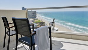 Un balcó amb dues cadires, una taula i vista a la platja i l'oceà.