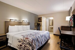 A hotel room with a large bed, a desk with a chair, a bathroom with a sink, and a TV. - Red Roof Inn Wilkes-Barre Arena (Wilkes-Barre)