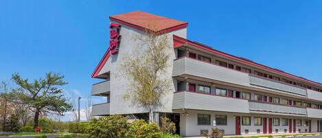 A motel with a red roof and a sign that reads 'Red Roof Inn.'