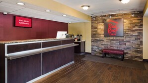 A hotel reception area with a red sign indicating free Wi-Fi, a stone wall with a Red Roof Inn logo, and a bench. - Red Roof Inn Wilkes-Barre Arena (Wilkes-Barre)