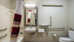 A bathroom with a bathtub, a sink, a toilet, a shower curtain, a towel rack, and a mirror. - Red Roof Inn Wilkes-Barre Arena (Wilkes-Barre)
