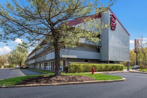 Un hotel Red Roof Inn con un diseño moderno, un estacionamiento y un hidrante rojo.