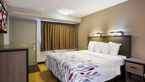 A hotel room with a bed, bedside tables, a desk, a television, and a window with curtains. - Red Roof Inn Wilkes-Barre Arena (Wilkes-Barre)